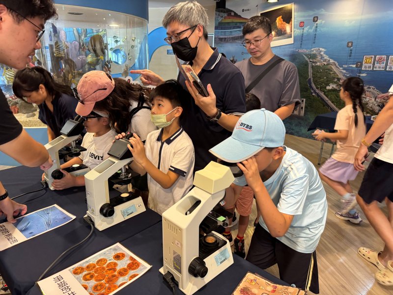 家長帶著孩子用顯微鏡觀察珊瑚
